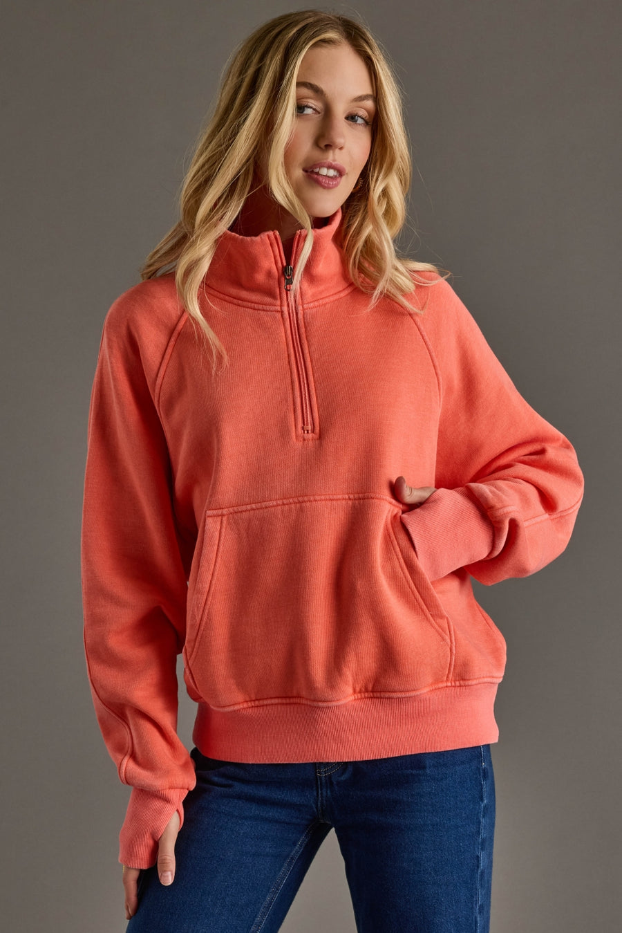Woman wearing a coral hoodie against a gray background