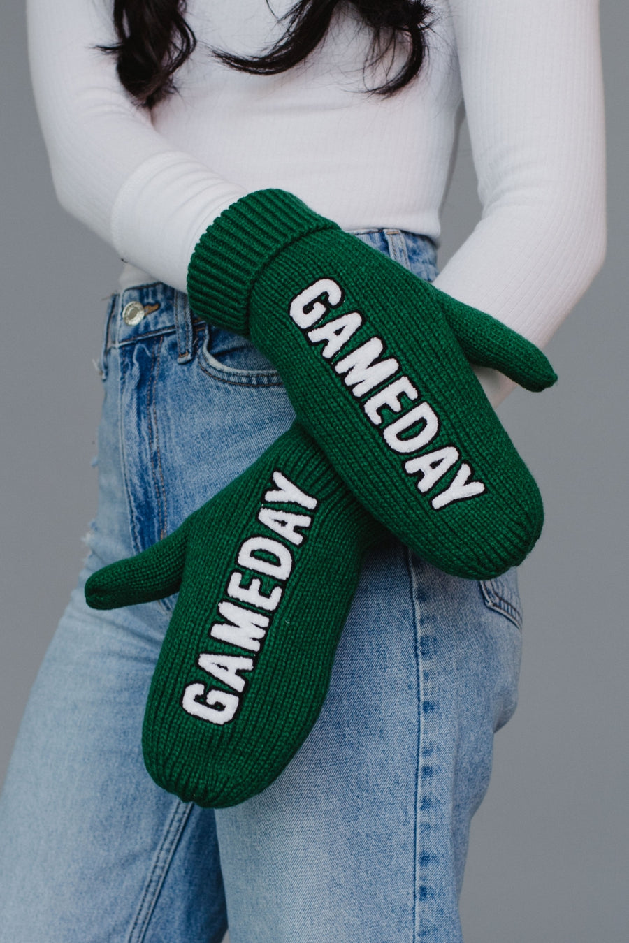 Green 'GAMEDAY' mittens worn by a person with a gray background