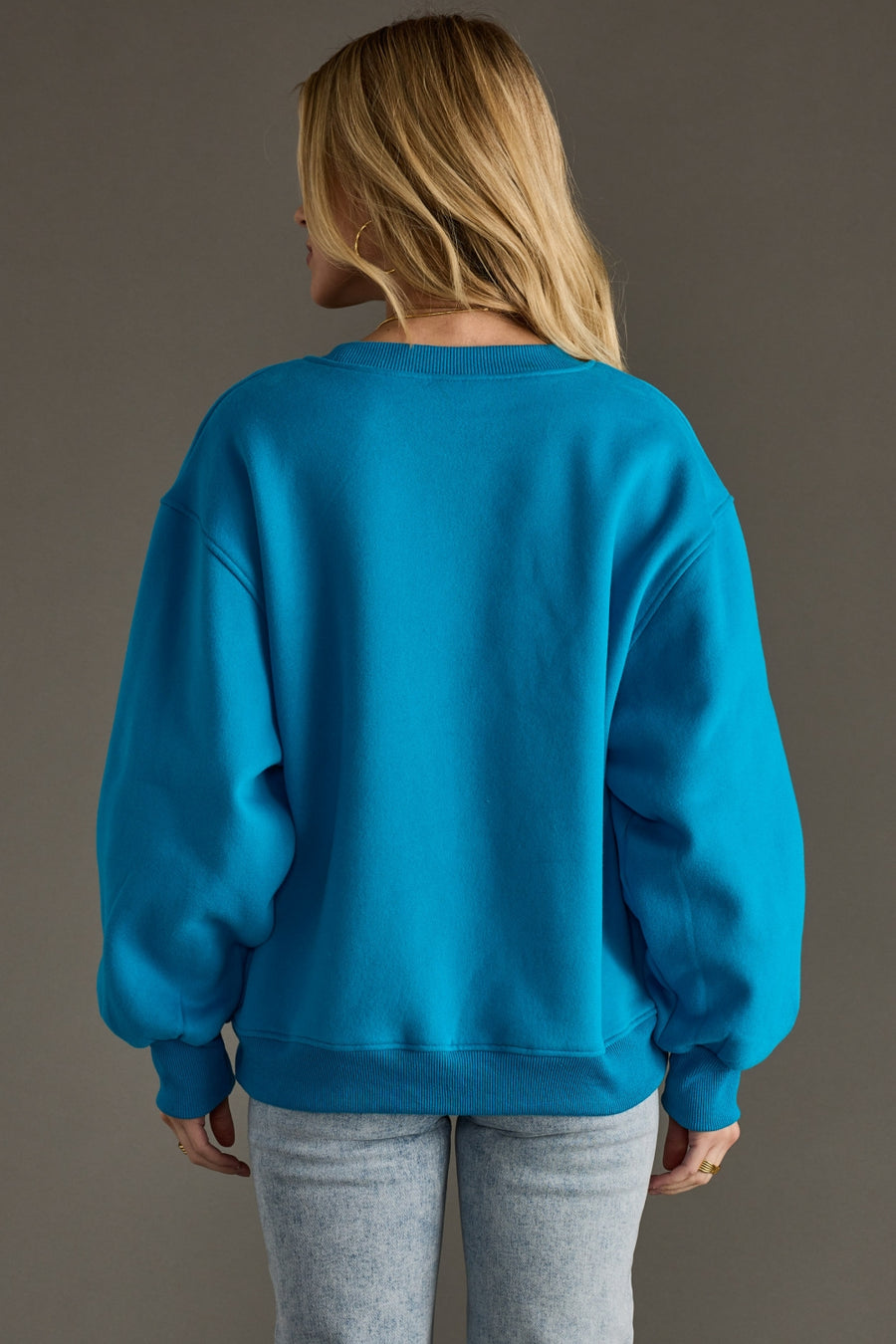 Person wearing a blue sweatshirt against a gray background