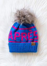 Blue knit beanie with pink text and gray pom-pom on a white background