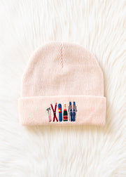 Pink beanie with embroidered ski icons on a white background