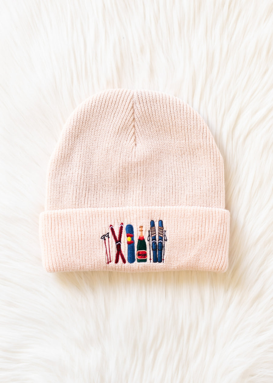 Pink beanie with embroidered ski icons on a white background