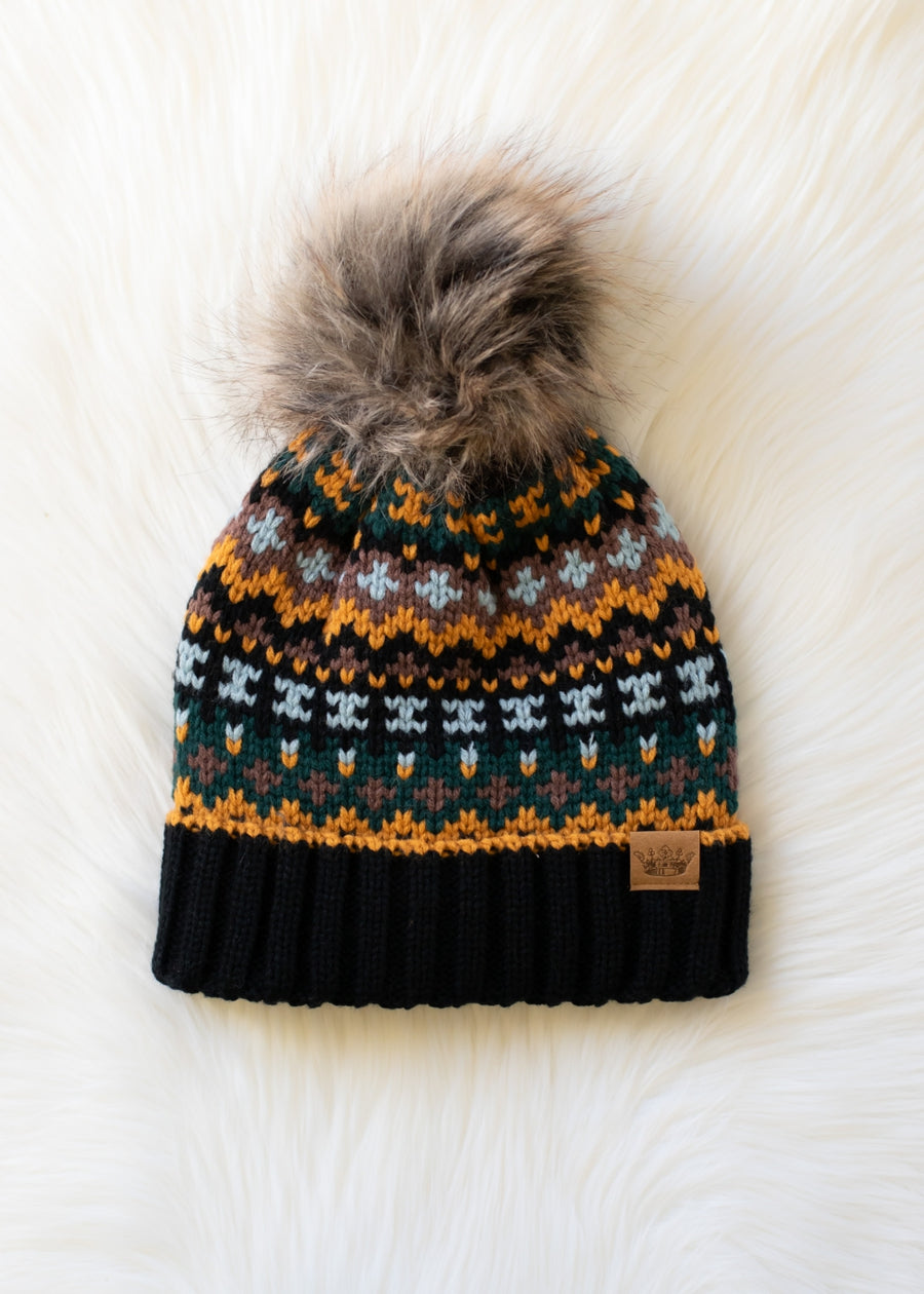 Knitted beanie with a patterned design and fur pom-pom on a white background