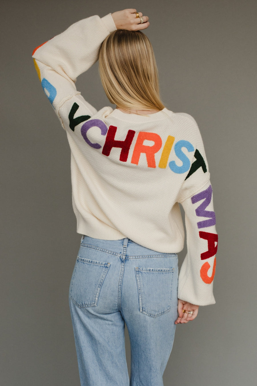 Ivory knit sweater with multicolored 'Merry Christmas' text on the back