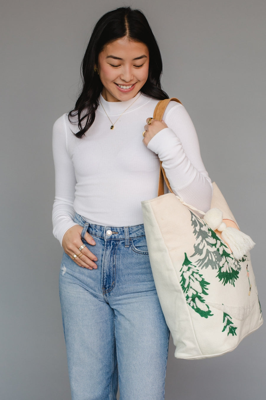 Woman holding a tote bag with a green design against a gray background