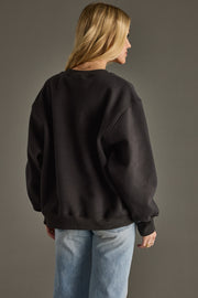 Person wearing a black sweatshirt and blue jeans against a gray background