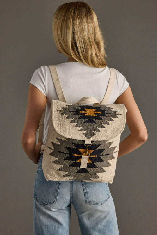 Person wearing a backpack with a geometric pattern on a plain background
