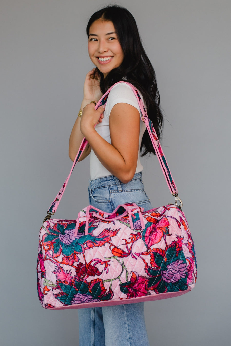 Woman holding a floral patterned handbag against a gray background