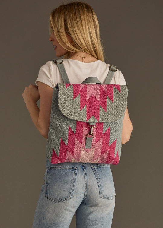 Person wearing a pink and gray patterned backpack against a plain background