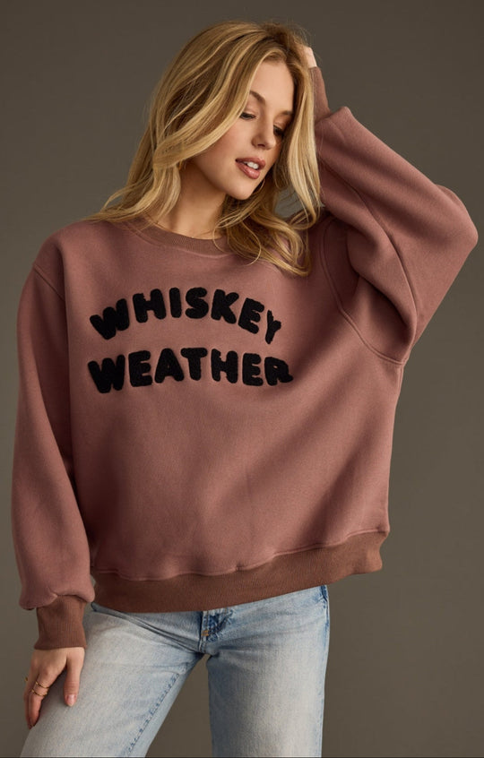 A cozy brown sweatshirt with bold black lettering that says “Whiskey Weather” — the ultimate cool-weather staple for laid-back nights and fireside hangs.
