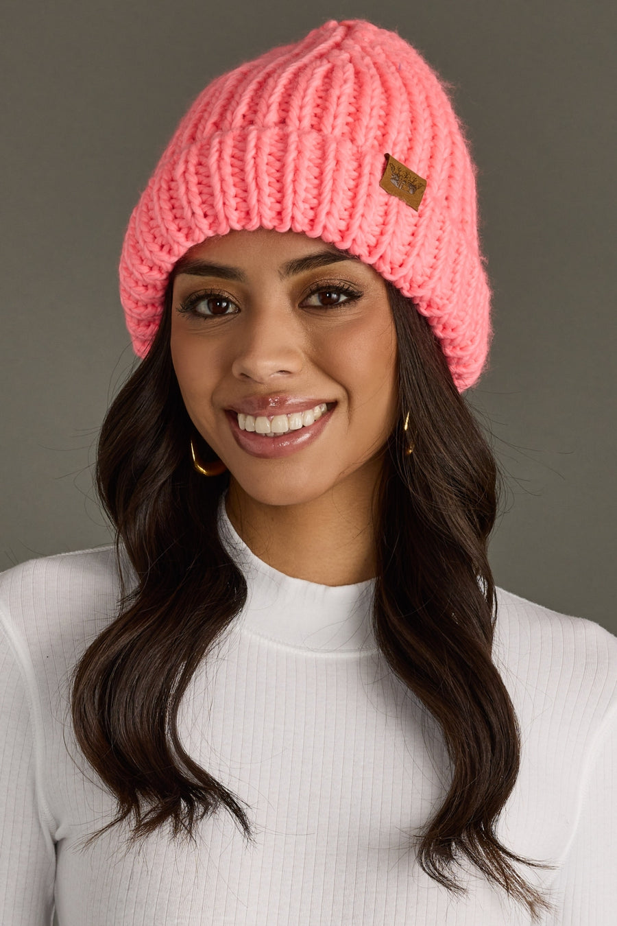 Woman wearing a pink knit beanie against a gray background