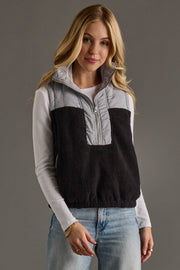 Woman wearing a black and gray half-zip sweater vest on a gray background