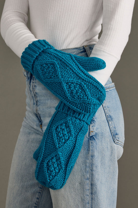 Teal knitted mittens worn by a person with a neutral background