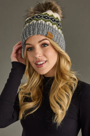 Woman wearing a gray knit beanie with a pom-pom on a gray background