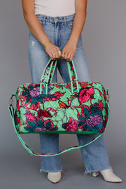 Person holding a floral patterned handbag with a plain background