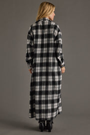 Woman wearing a long black and white checkered coat against a gray background