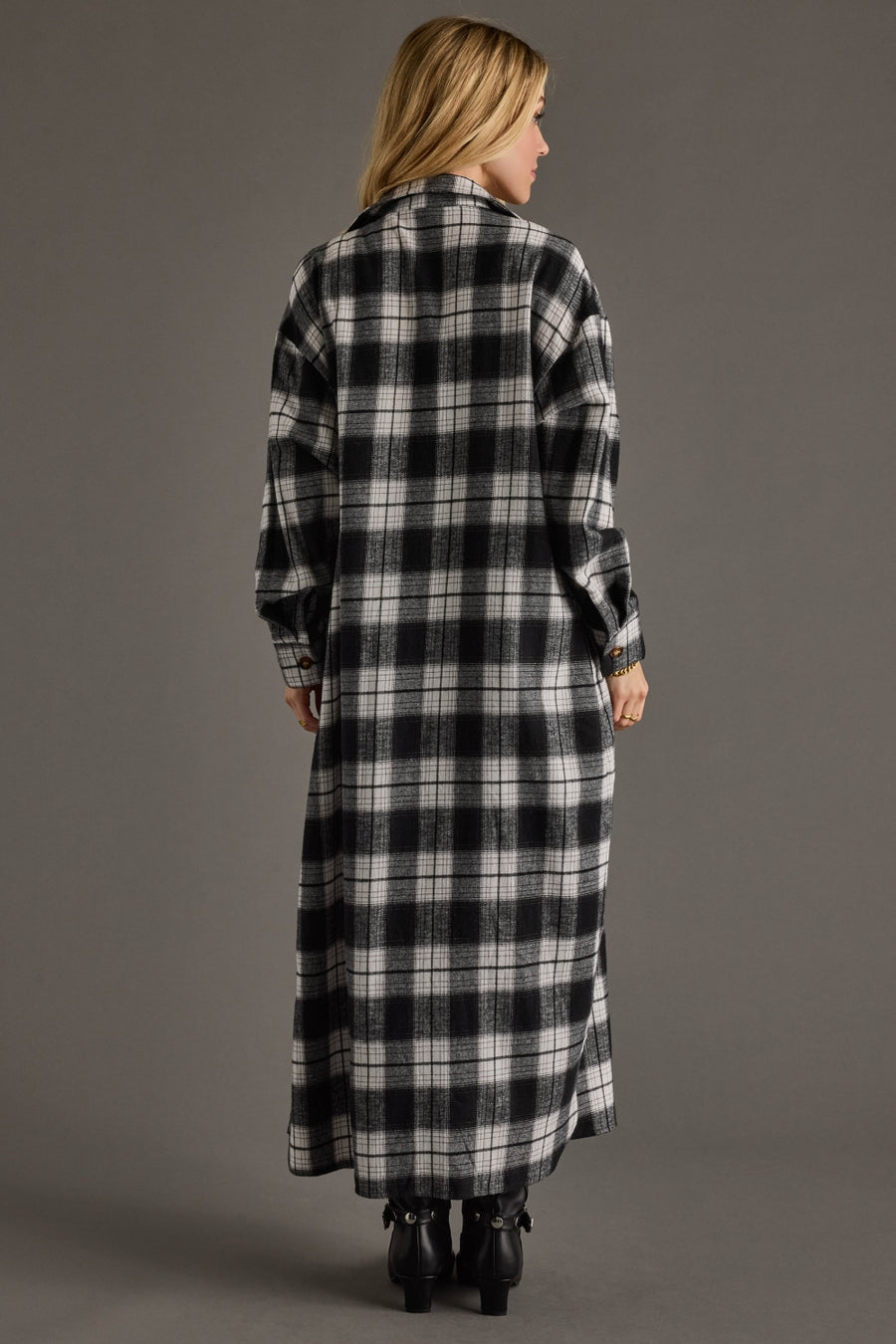 Woman wearing a long black and white checkered coat against a gray background