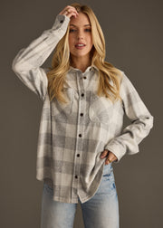 Woman wearing a plaid shirt and jeans against a brown background