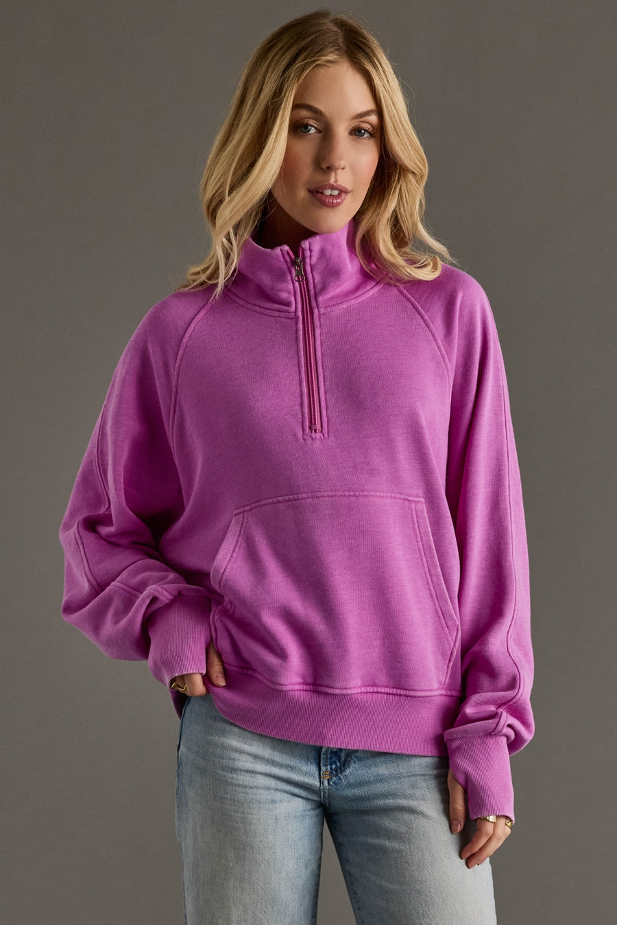 Woman wearing a purple pullover with a quarter zip on a gray background