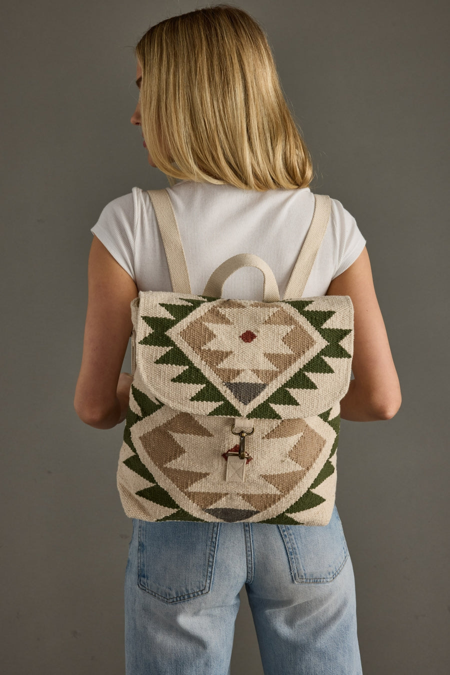 Person wearing a backpack with geometric pattern on a plain background