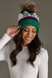 Woman wearing a colorful knit beanie with a pom-pom on a gray background