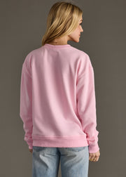 Person wearing a pink sweatshirt and blue jeans on a plain background