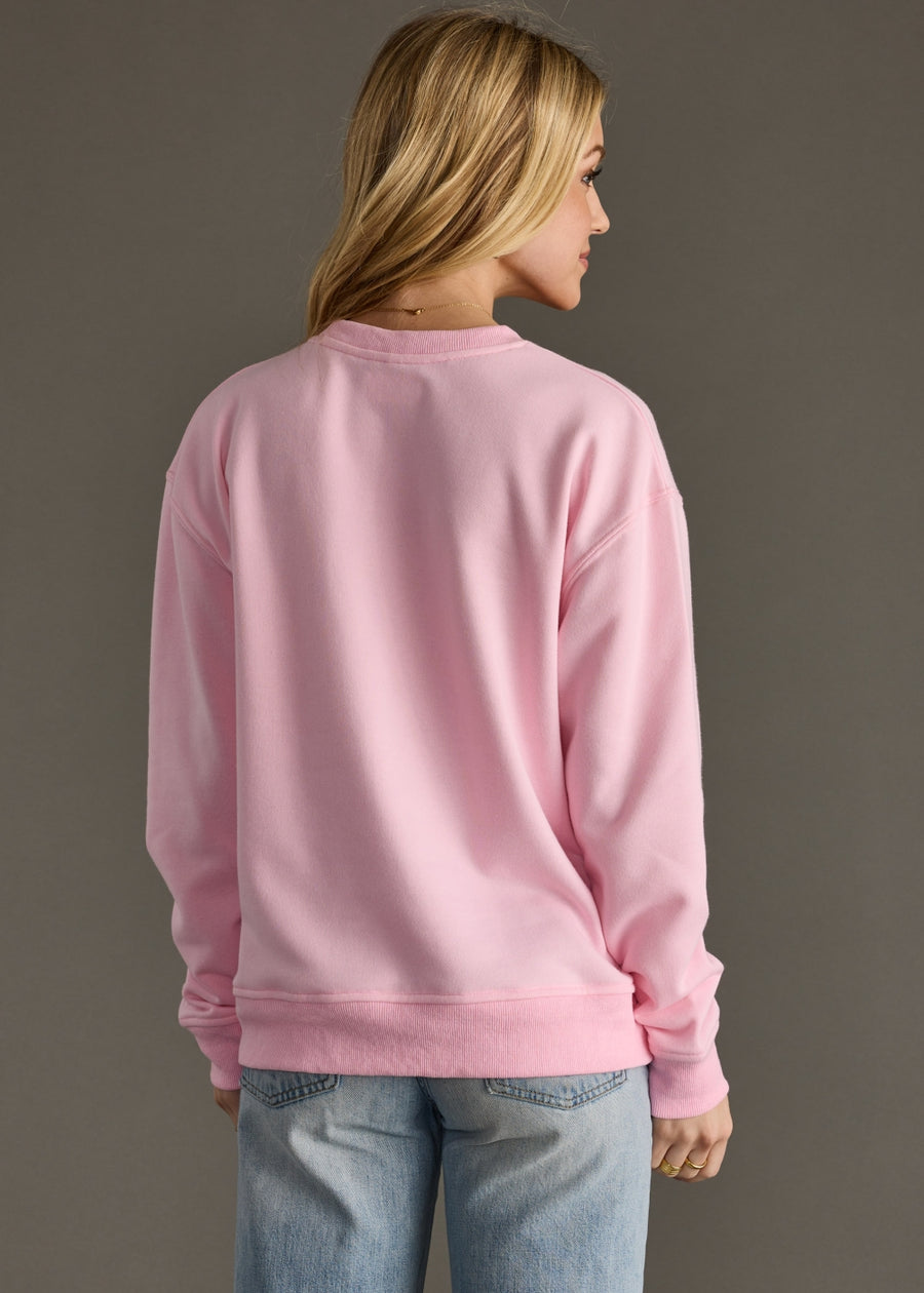 Person wearing a pink sweatshirt and blue jeans on a plain background