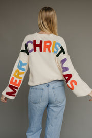 Ivory knit sweater with multicolored 'Merry Christmas' text on the back