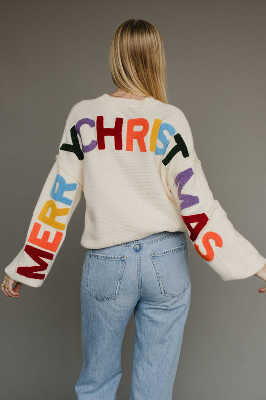 Ivory knit sweater with multicolored 'Merry Christmas' text on the back