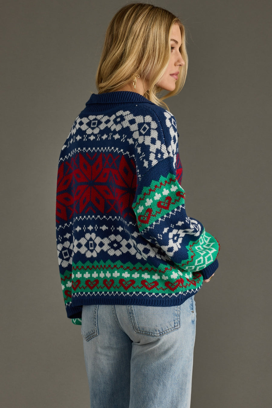Person wearing a colorful patterned sweater against a gray background