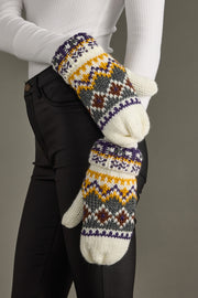 Person wearing a pair of patterned mittens against a neutral background