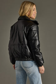 Person wearing a black leather jacket and light blue jeans against a gray background