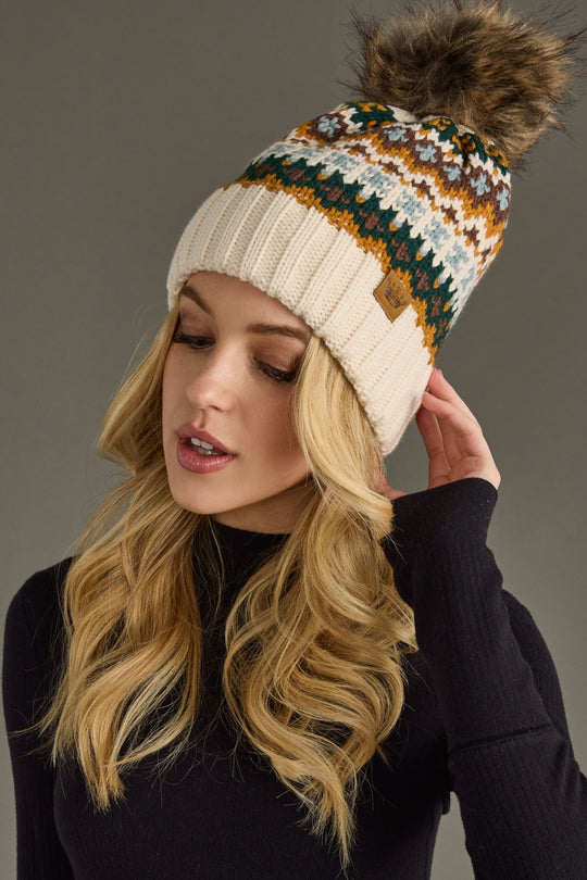 Woman wearing a patterned knit beanie with a pom-pom on a gray background