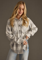 Woman wearing a plaid shirt and jeans against a dark background