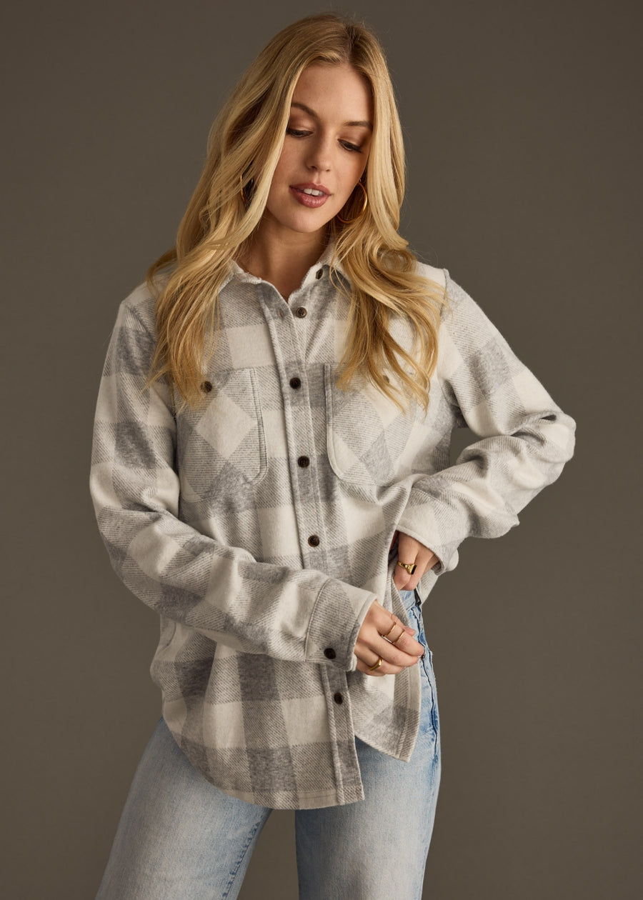 Woman wearing a plaid shirt and jeans against a dark background