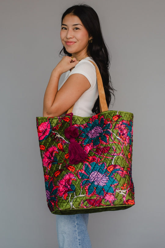Woman holding a colorful floral tote bag against a plain background