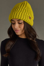 Woman wearing a lime green knit beanie against a gray background