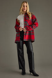 Woman wearing a red plaid coat over a white shirt with black pants on a gray background