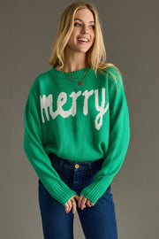 Woman wearing a green sweater with 'merry' text on a gray background