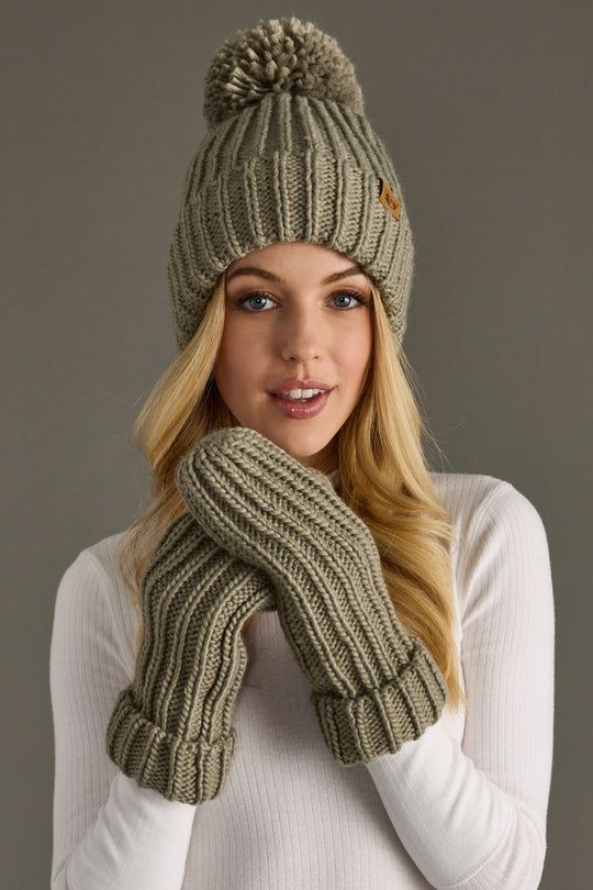 Woman wearing a matching green knit hat and mittens set against a neutral background