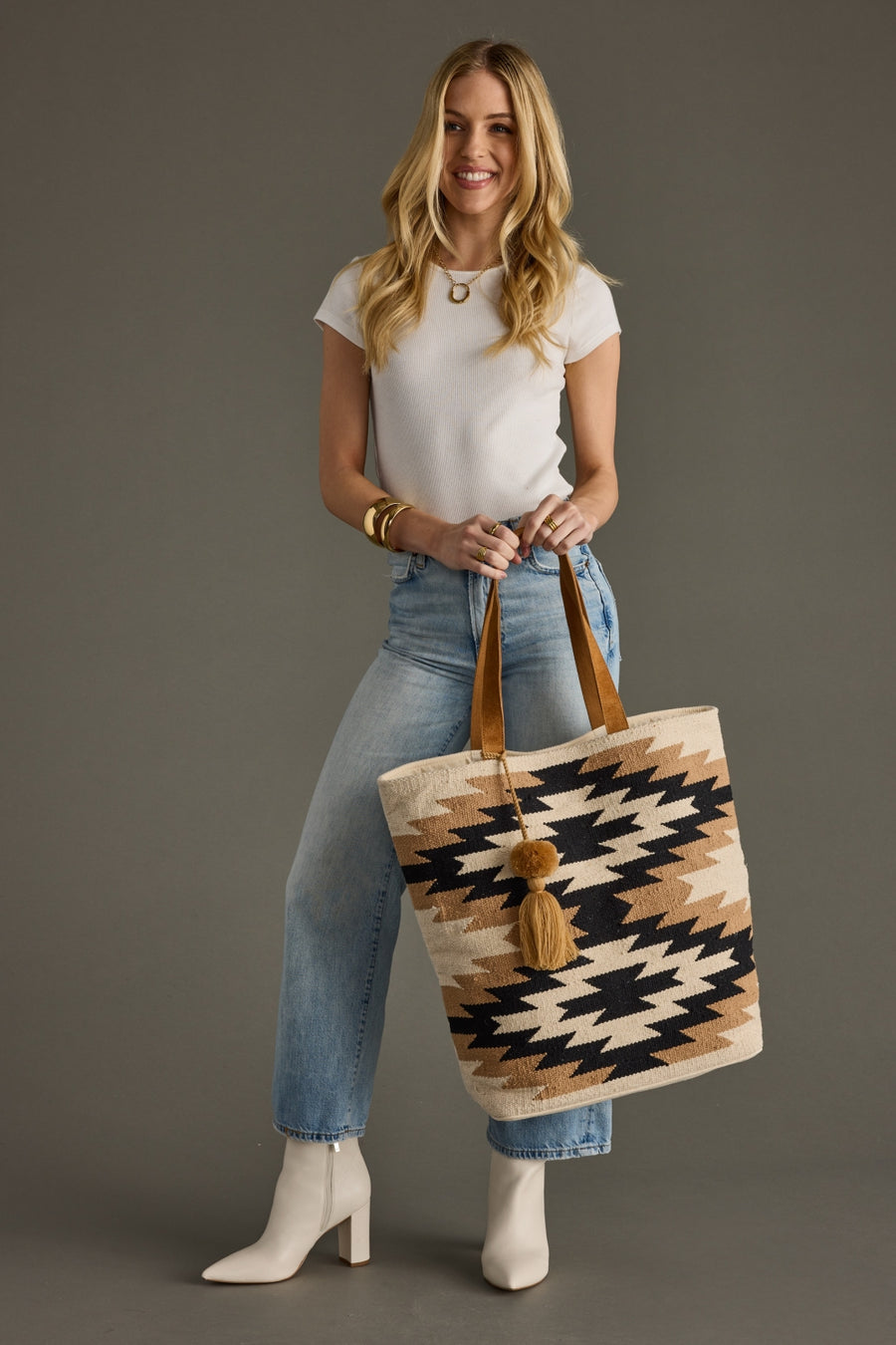 Woman holding a patterned tote bag against a gray background