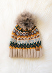 Knitted beanie with a pattern and fur pom-pom on a white background