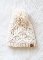 Knitted cream beanie with a pom-pom on a white background