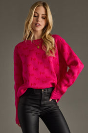 Woman wearing a bright pink sweater with red text against a gray background