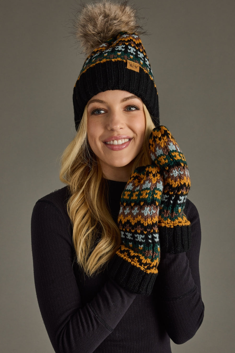 Woman wearing a patterned knit hat and mittens on a gray background