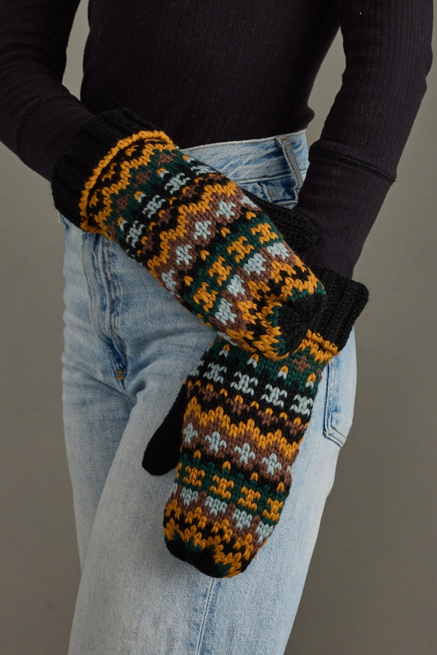 Person wearing patterned mittens with a plain background