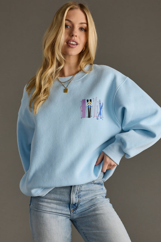 Woman wearing a light blue sweatshirt with a colorful graphic on a gray background
