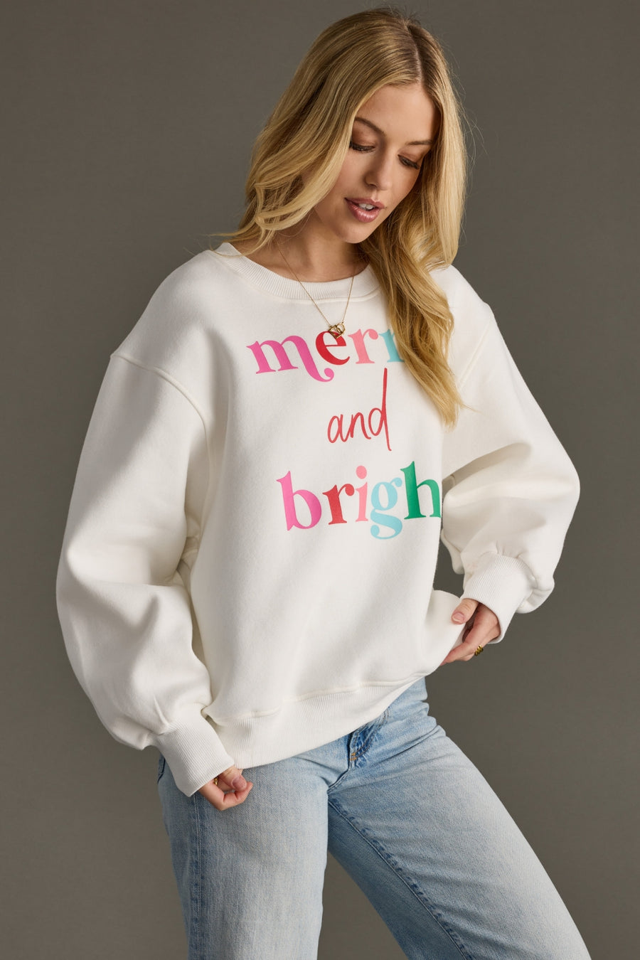 Woman wearing a white sweatshirt with colorful text on a gray background