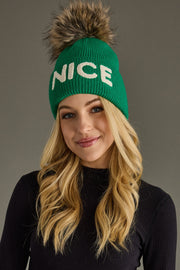 Woman wearing a green beanie with 'NICE' text against a gray background