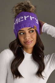 Woman wearing a purple knit headband with 'Merry' text against a gray background